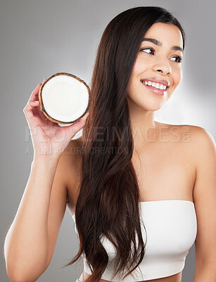 Buy stock photo Studio shot of a beautiful young woman posing with a coconut against a grey background