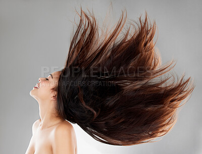 Buy stock photo Studio shot of a beautiful young woman with flowing hair against a grey background