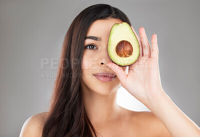 Buy stock photo Studio portrait of a beautiful young woman posing with an avocado against a grey