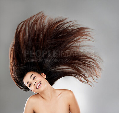 Buy stock photo Studio portrait of a beautiful young woman with flowing hair against a grey background