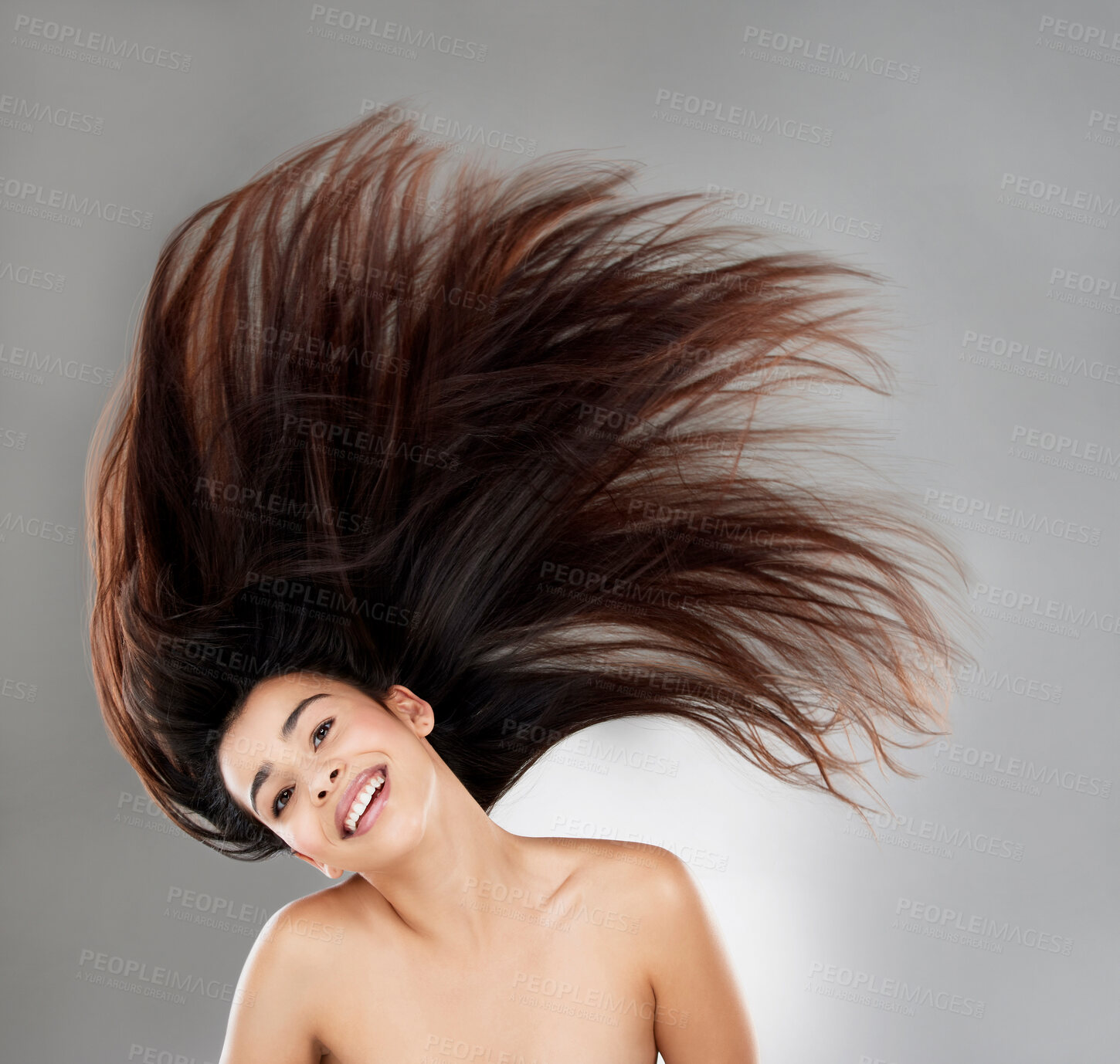Buy stock photo Studio portrait of a beautiful young woman with flowing hair against a grey background