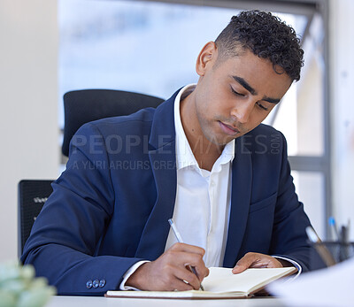Buy stock photo Shot of a young businessman writing notes while working in an office