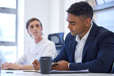 Buy stock photo Shot of a young businessman writing notes during a meeting in an office