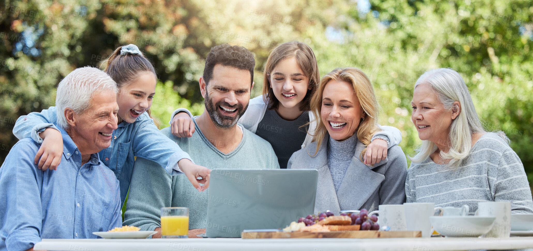 Buy stock photo Shot of a family using a laptop outside