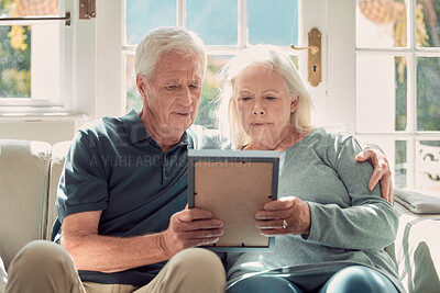 Buy stock photo Senior couple, memory and picture frame for nostalgia, history or remember past together in home. Retirement, man and woman hold photo for sad reminder of loss, grief or missing person in living room