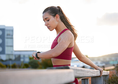 Buy stock photo Shot of a young woman checking the time while working out outside