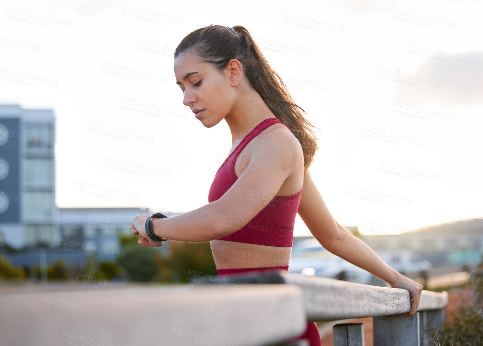 Buy stock photo Shot of a young woman checking the time while working out outside