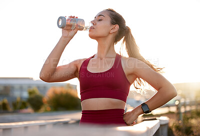 Buy stock photo Shot of a young woman drinking water while exercising in the city