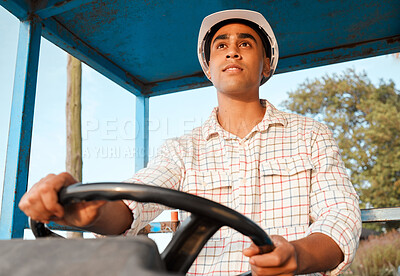 Buy stock photo Shot of a young farmer driving a tractor on a farm