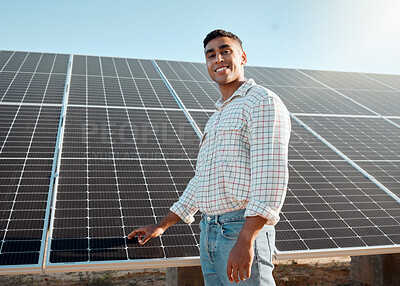 Buy stock photo Shot of a young man standing next to a solar panel on a farm