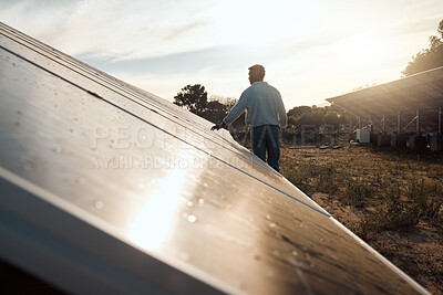Buy stock photo Shot of a young man standing next to a solar panel on a farm