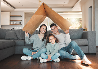 Buy stock photo Shot of a young family sitting on the lounge floor under a cardboard fort together at home