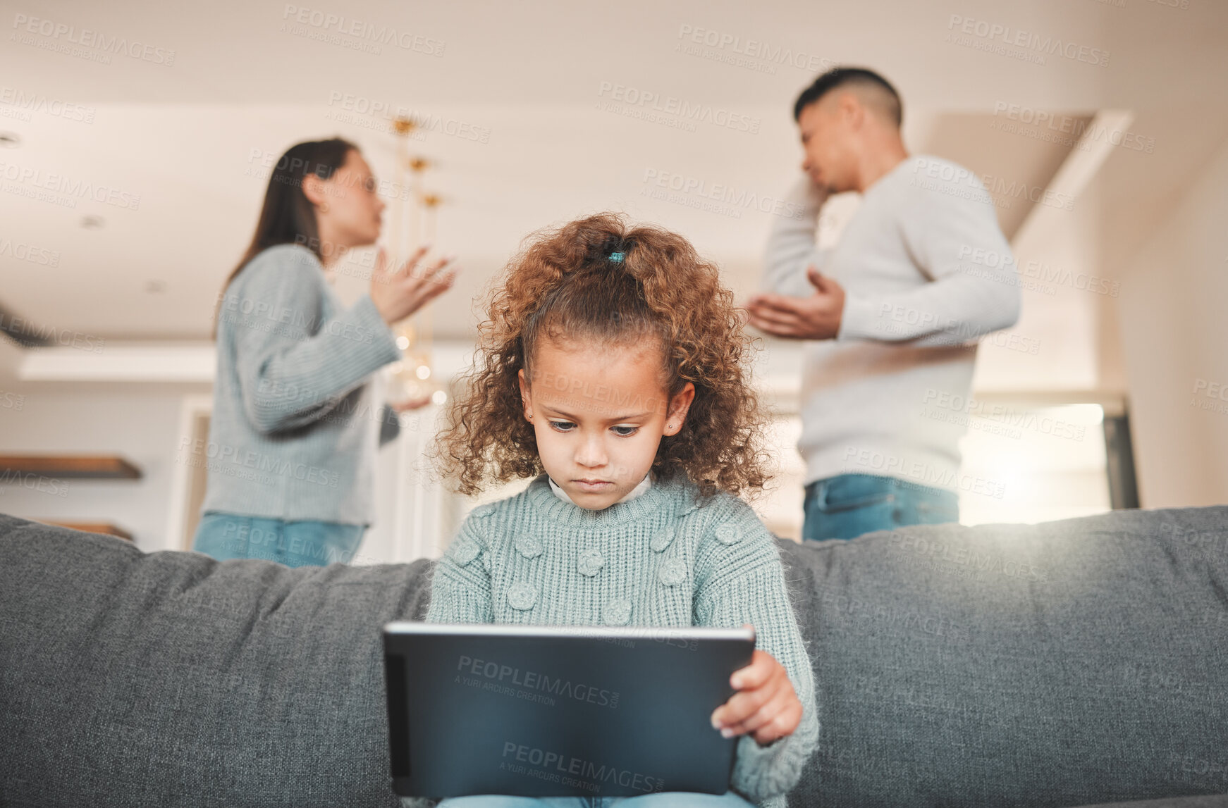 Buy stock photo Shot of a little girl using a digital tablet to listen to music while her parents argue