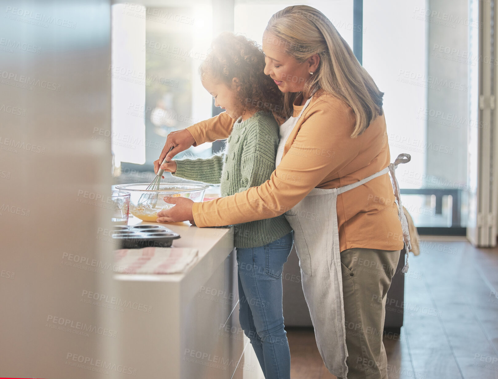 Buy stock photo Shot of a woman baking with her granddaughter at home