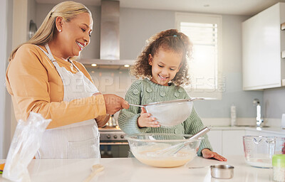 Buy stock photo Shot of a woman baking with her granddaughter at home