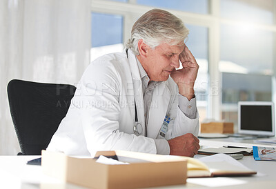 Buy stock photo Shot of a mature doctor suffering from a headache at work
