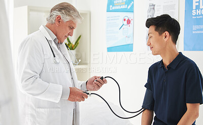 Buy stock photo Shot of a mature doctor monitoring a patient's blood pressure at a hospital