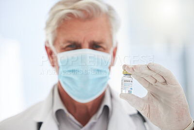 Buy stock photo Shot of a mature doctor holding a vaccine vial at a hospital