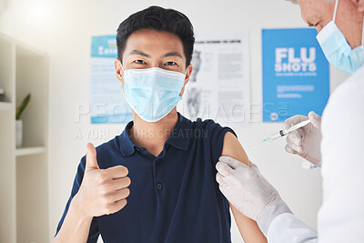 Buy stock photo Shot of a young man showing a thumbs up while getting a vaccination at a hospital