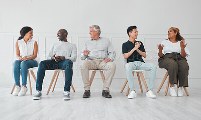 Buy stock photo Shot of a group of diverse people talking to each other while sitting in line against a white background