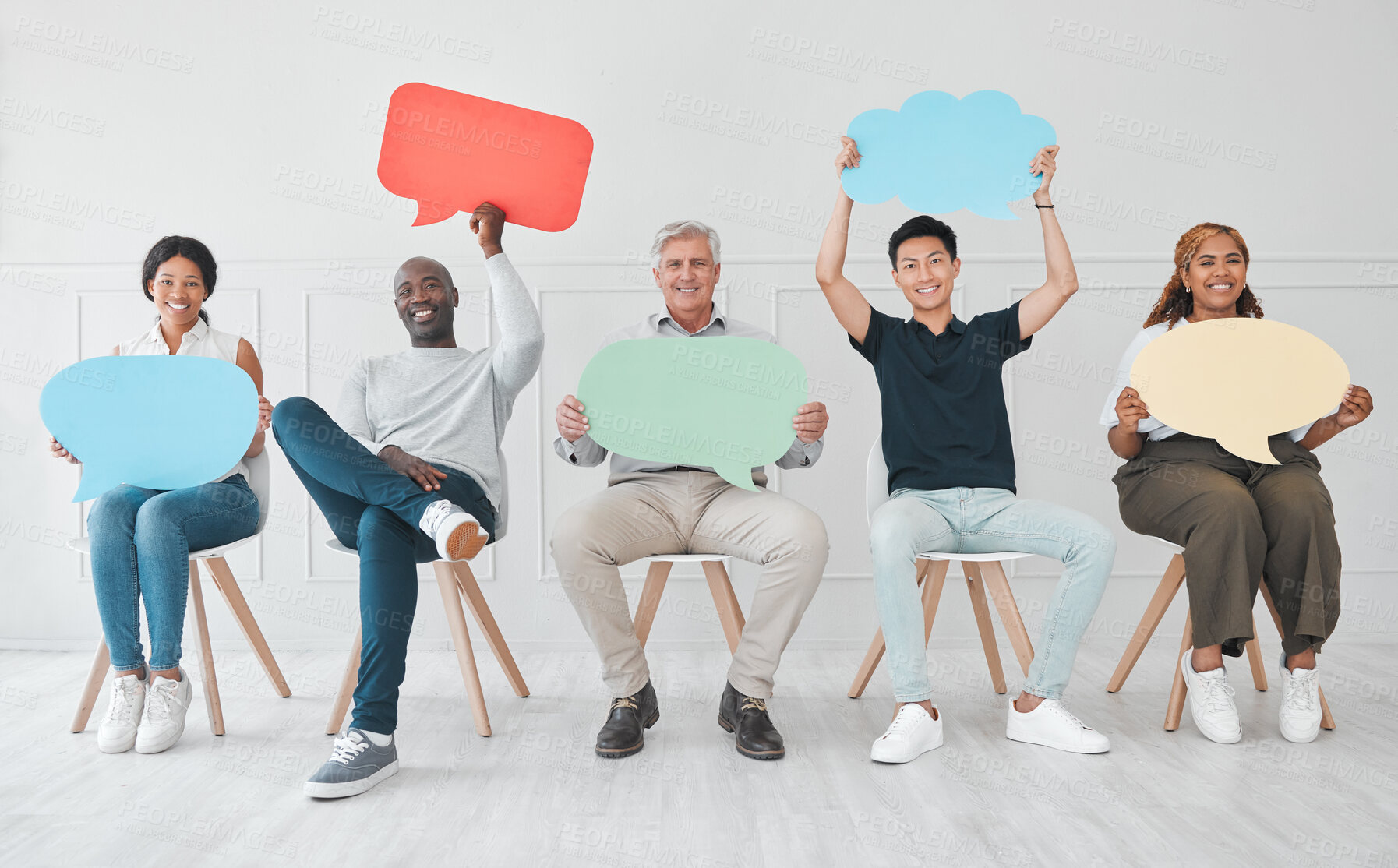 Buy stock photo Portrait of a diverse group of people holding colourful speech bubbles while sitting in line against a white background