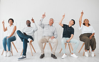 Buy stock photo Shot of a diverse group of people pointing up while sitting in line against a white background