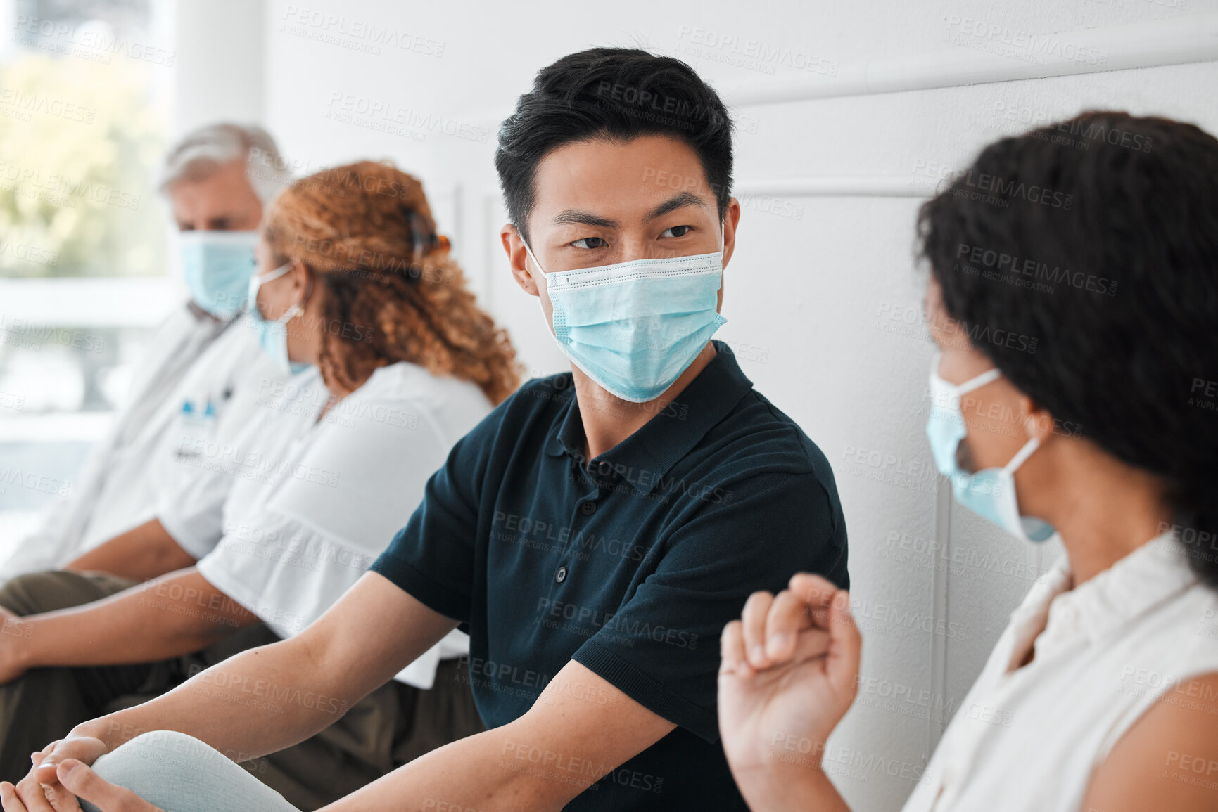 Buy stock photo Shot of a group of people wearing face masks while sitting in a queue