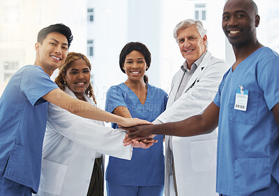 Buy stock photo Portrait of a group of medical practitioners joining their hands together in a huddle in a hospital