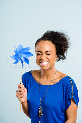 Buy stock photo Shot of an attractive young woman sitting alone in the studio and holding a pinwheel