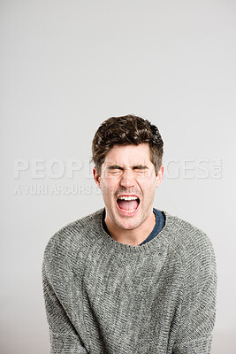 Buy stock photo Shot of a handsome young man sitting alone in the studio and screaming