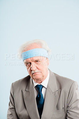 Buy stock photo Shot of a senior man sitting alone in the studio and looking grumpy while wearing a headband