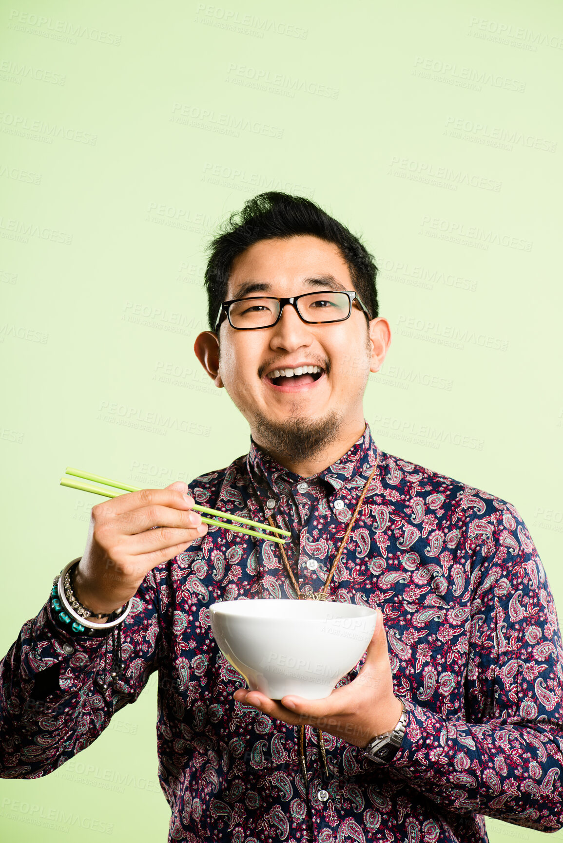 Buy stock photo Studio, portrait and asian man with chopstick for eating, nutrition and laughing with confidence. Mockup space, male person and bowl by green background for meal, noodles and food with happiness