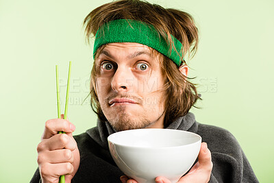 Buy stock photo Portrait, bowl and hungry man with chopsticks for Chinese food or dinner isolated on green background. Face, empty and person waiting for eating, share or asking for lunch donation for diet in studio