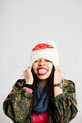 Buy stock photo Shot of an attractive young woman sitting alone in the studio and putting her beanie on