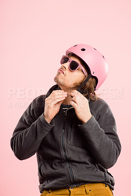 Buy stock photo Shot of a handsome young man standing alone in the studio and putting a helmet on