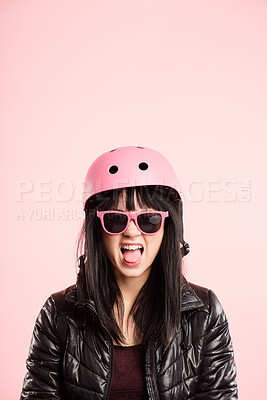 Buy stock photo Shot of an attractive young woman sitting alone in the studio and pulling a funny face while wearing a helmet