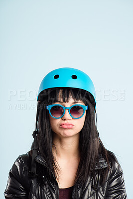Buy stock photo Shot of an attractive young woman sitting alone in the studio and pulling a funny face while wearing a helmet