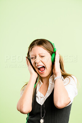 Buy stock photo Shot of an attractive young woman standing alone in the studio and listening to music through headphones