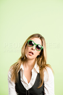 Buy stock photo Shot of an attractive young woman standing alone in the studio and looking bored while wearing sunglasses