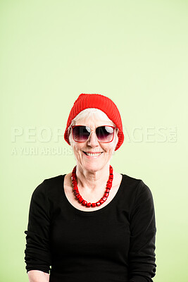 Buy stock photo Shot of a senior woman sitting alone in the studio and posing while wearing a beanie and sunglasses