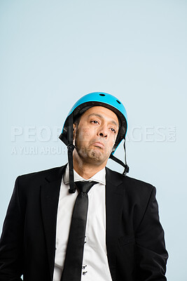 Buy stock photo Shot of a handsome young businessman sitting alone in the studio and posing while wearing a helmet