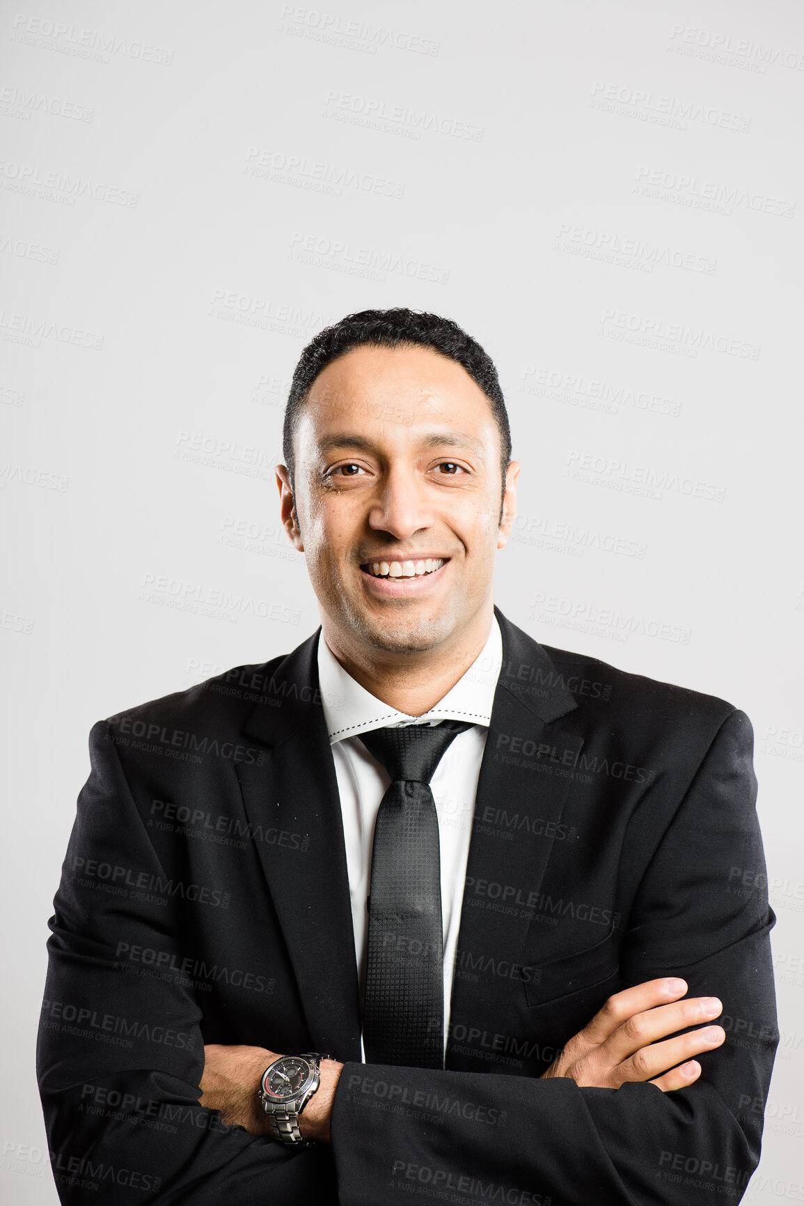 Buy stock photo Shot of a handsome young businessman standing alone in the studio and posing with his arms folded