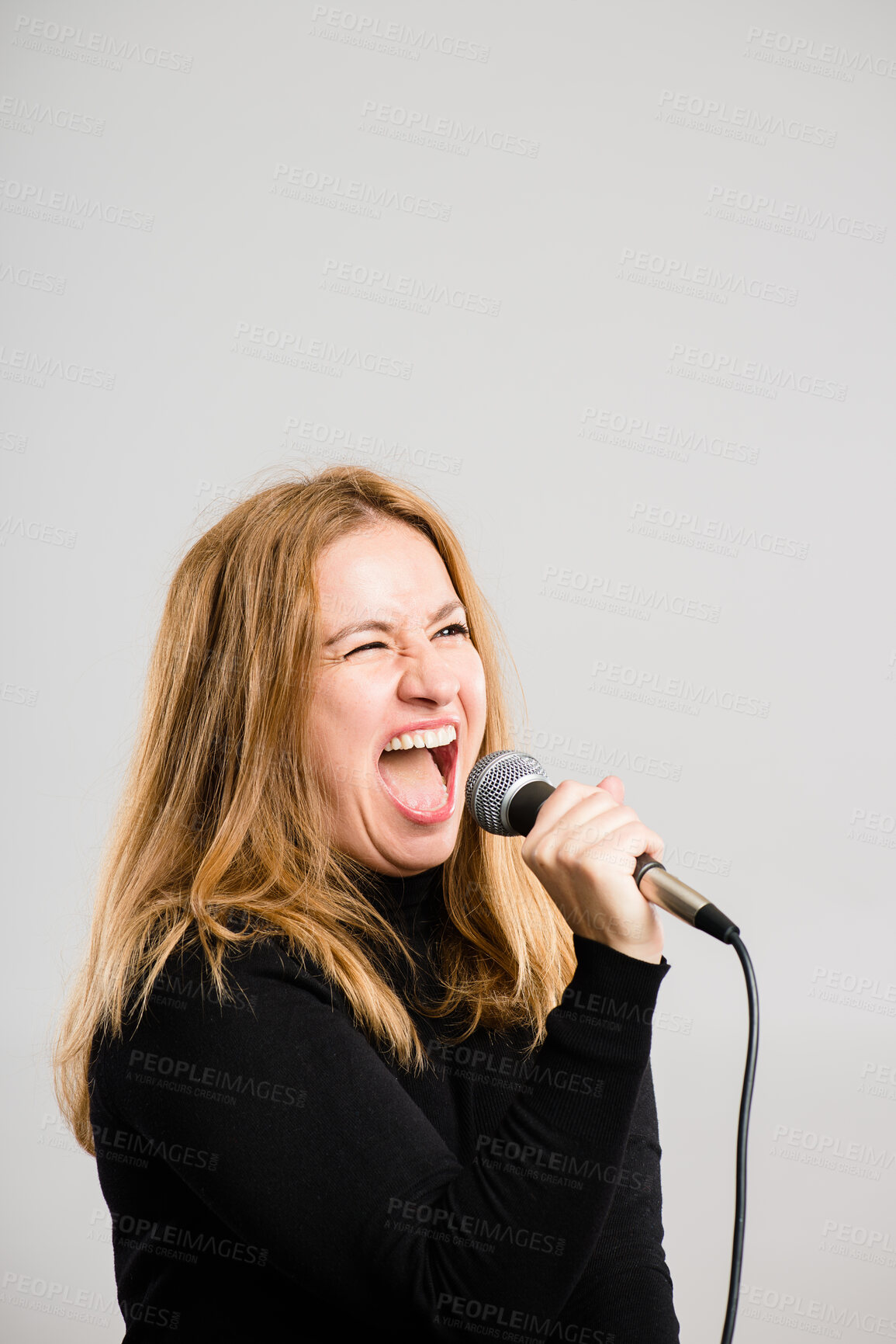 Buy stock photo Woman, microphone and karaoke in studio with mock up space, singing or voice by white background. Person, performance or concert with music, sound and audio tech with promotion for album sales