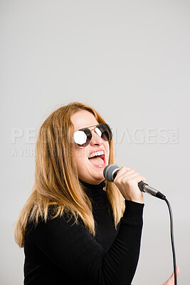 Buy stock photo Woman, microphone and singing with sunglasses in studio by mockup space, rock or voice by white background. Person, performance or concert with music, sound and audio tech with event for album sales