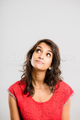 Buy stock photo Shot of an attractive young woman sitting alone in the studio and looking contemplative