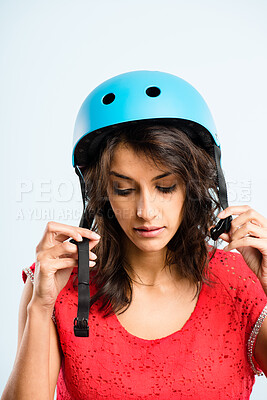 Buy stock photo Shot of an attractive young woman standing alone in the studio and putting a helmet on