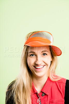 Buy stock photo Woman, portrait and happy with visor, fashion and smile with funky style in studio and mockup. Hat, confidence and female person from Germany with color, fun and cool cap with green background