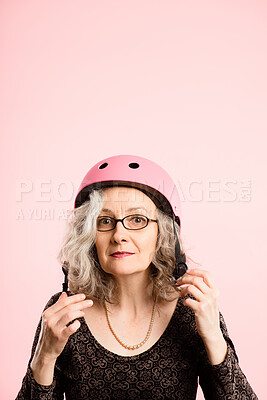 Buy stock photo Shot of a senior woman standing alone in the studio and putting a helmet on
