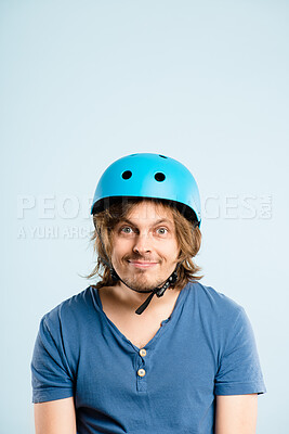 Buy stock photo Shot of a handsome young man sitting alone in the studio and posing while wearing a helmet