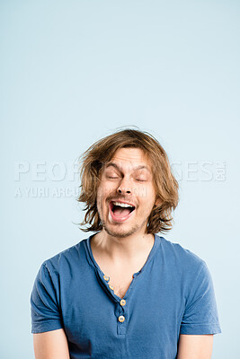 Buy stock photo Shot of a handsome young man standing alone in the studio and pulling a funny face